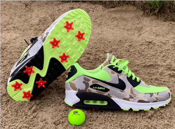Camo Air Max 90 with red spikes next to a lime golf ball