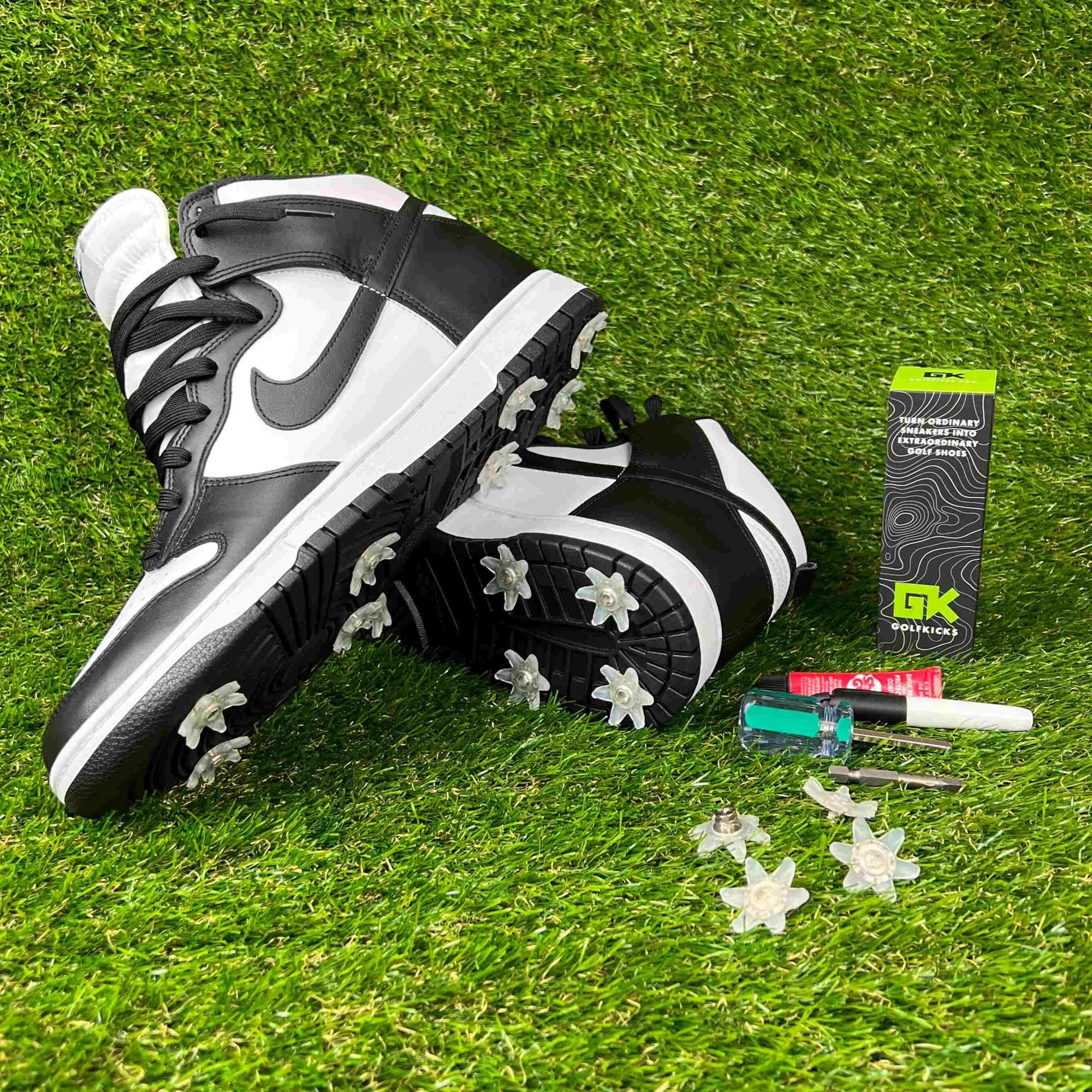 Black and white high-top sneakers with spikes, kit box and tools on the grass